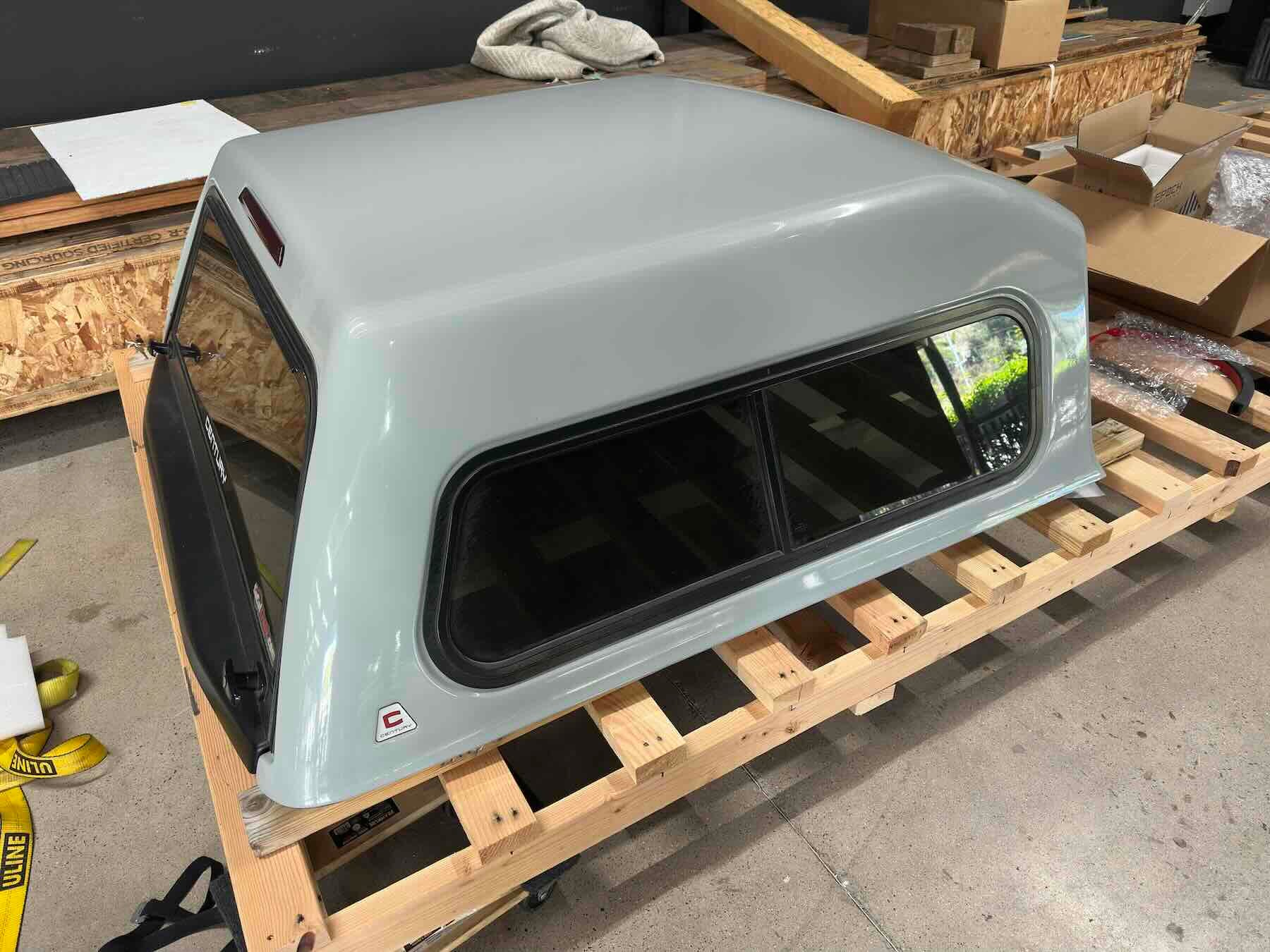 Gray Century truck cap with windows on a wooden pallet in an indoor setting