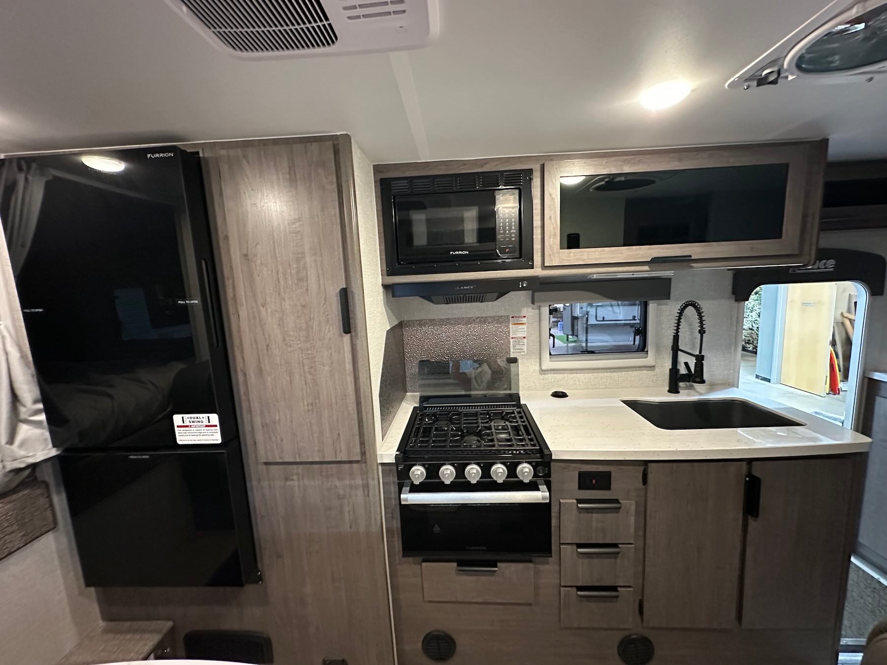 Kitchen area inside Lance 1191 with fridge, stove, oven , microwave, sink and cabinets.