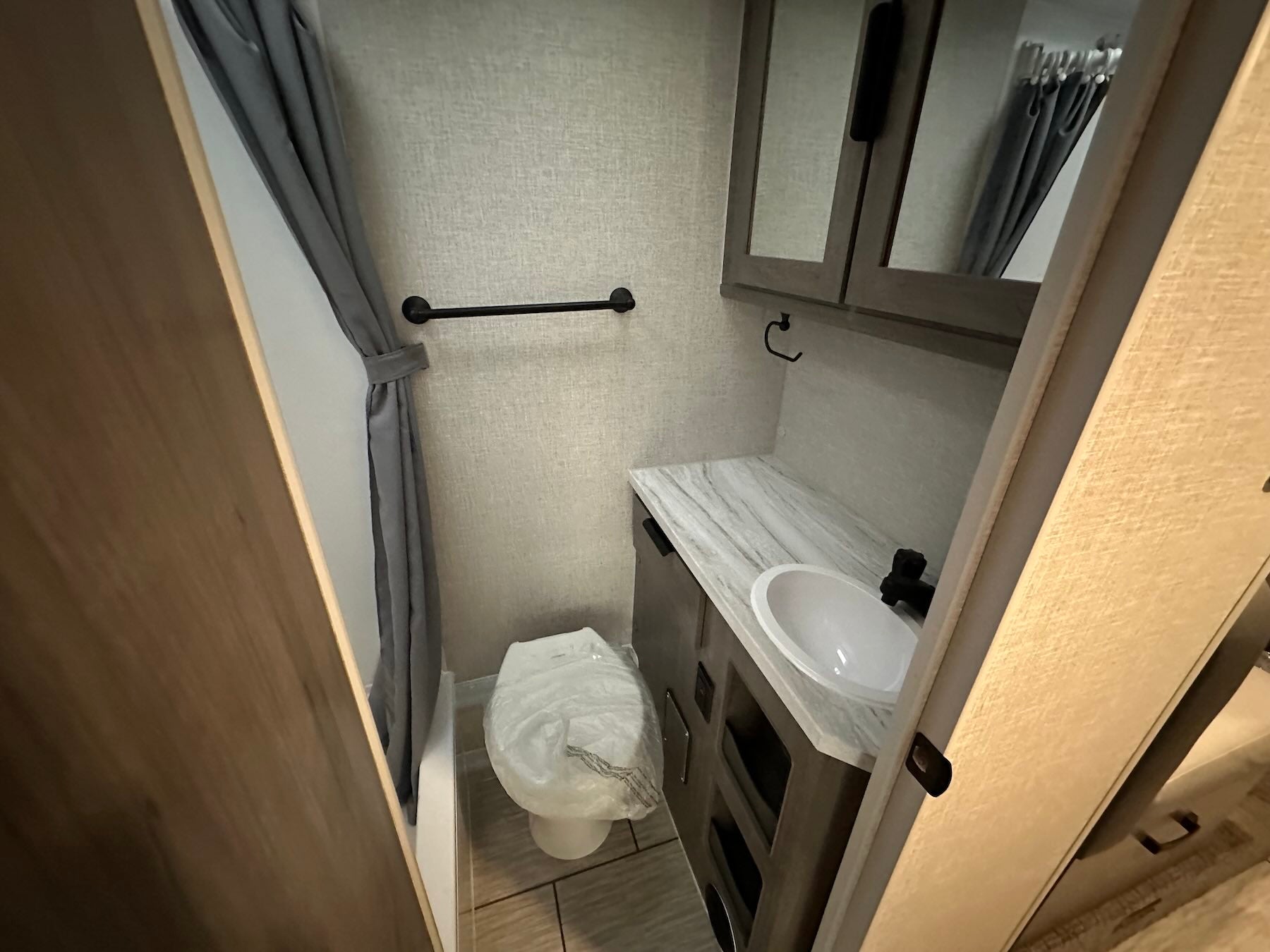 Lance 1191 bathroom interior with toilet, sink, and mirror.