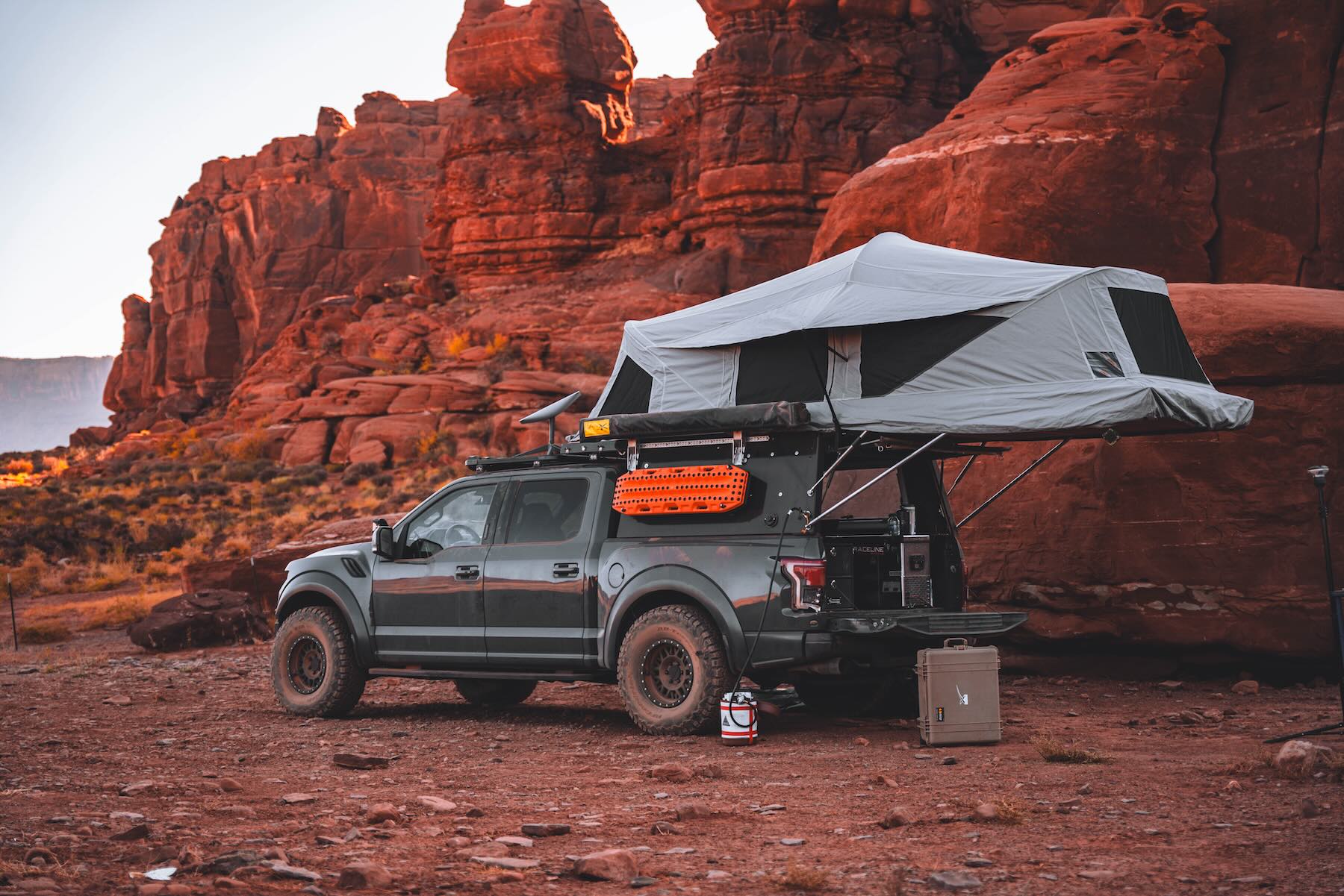 AT Overland Habitat truck topper deployed on a dark grey pickup truck with a red desert rock background