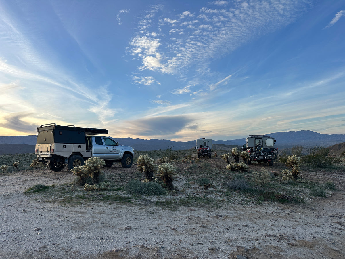 A group of trucks with campers parked together in the desert
