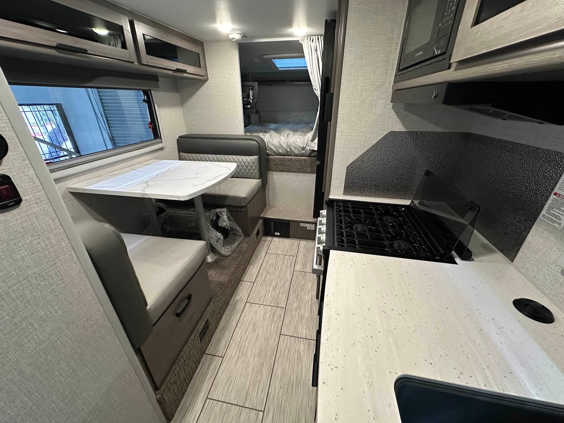 Interior of a Lance 1191  truck camper with a kitchen area, dinette area, and view of the cabover bed
