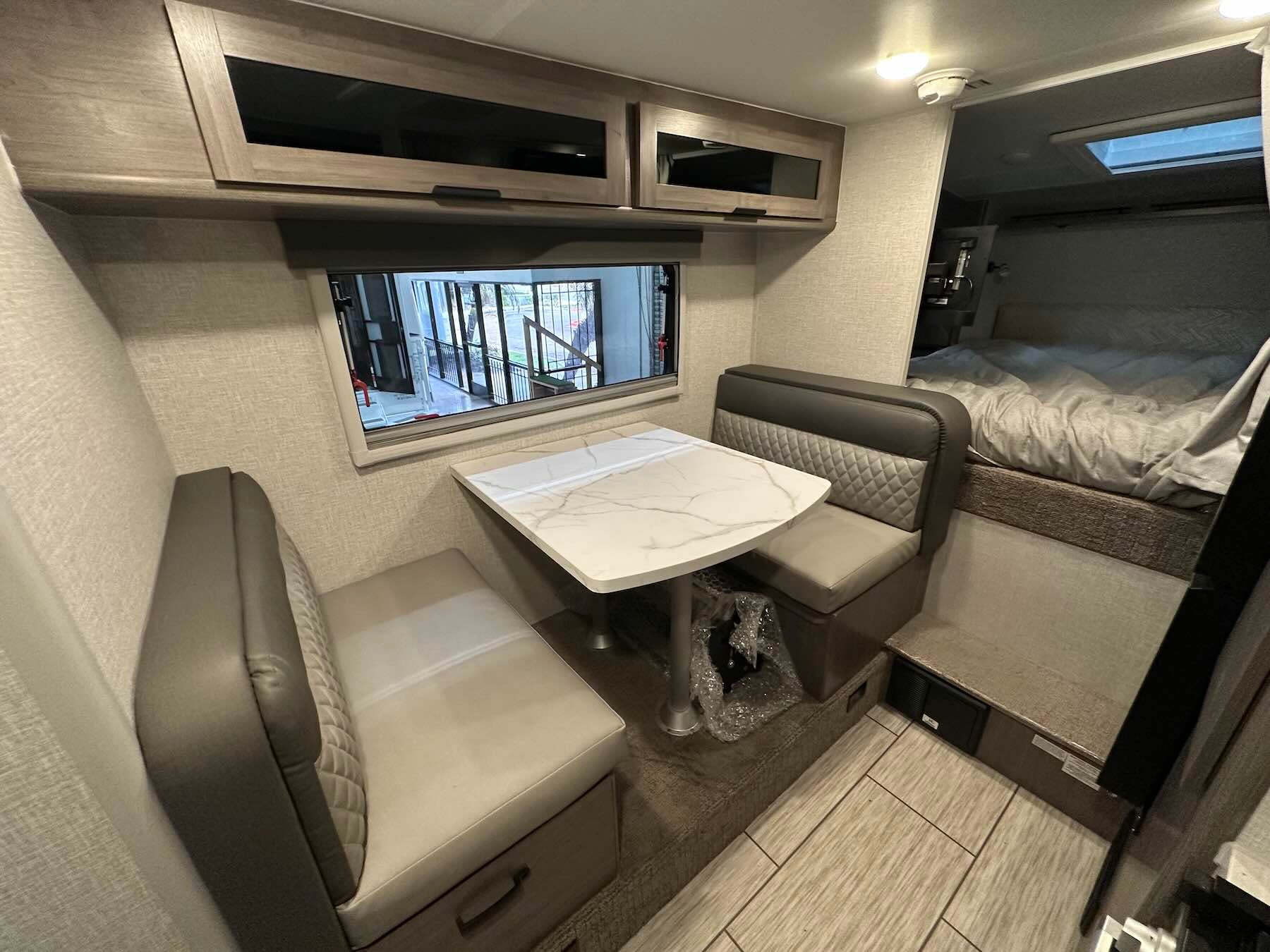 Interior of Lance 1191 showing dinette set, side window, bed, and overhead cabinets.