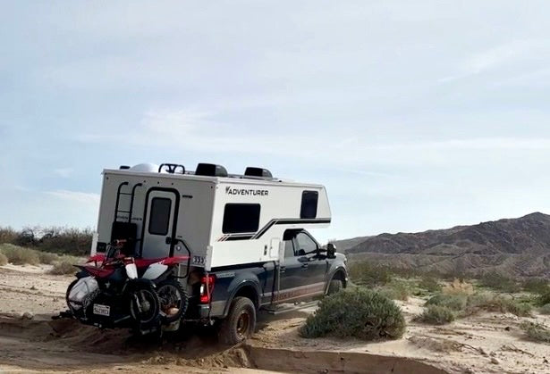 Truck camper rig on a rough desert road with the suspension loaded