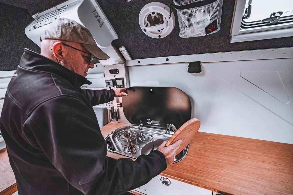 Man opening integrated sink and stovetop in AT Overland Flatbed Camper