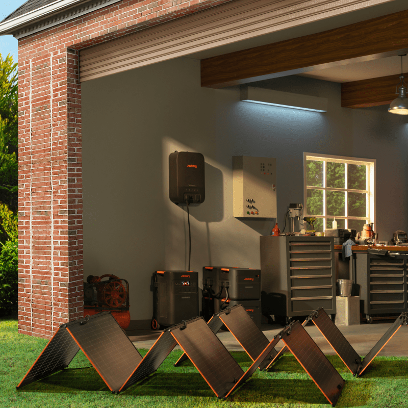 Solar panels in front of a garage with a home energy system on the wall.
