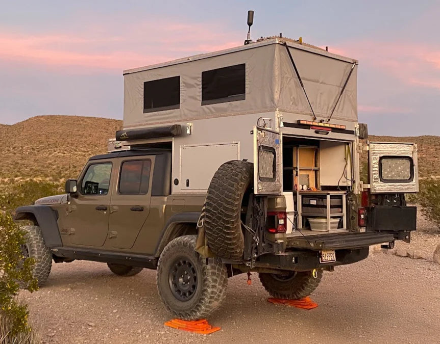 Camper truck in a desert landscape with a pink sky
